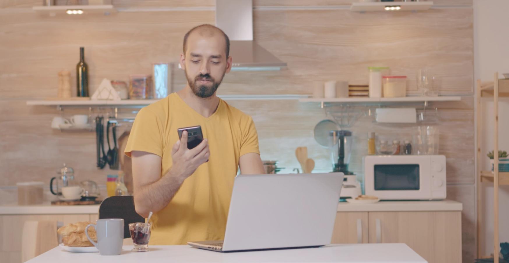 Personne analysant ses documents financiers avec un ordinateur portable et des notes manuscrites sur un bureau lumineux